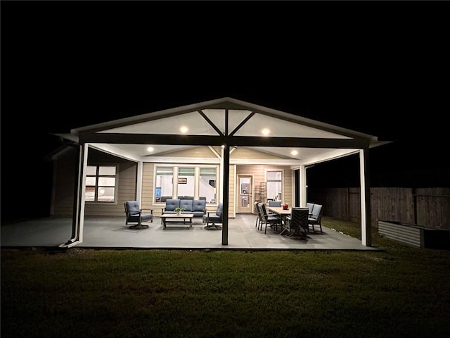 back of house at twilight with a yard, an outdoor hangout area, a patio, and fence