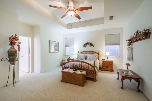 bedroom with a tray ceiling, visible vents, carpet floors, and ceiling fan