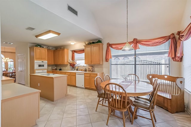 kitchen with white appliances, light brown cabinets, visible vents, light countertops, and a center island