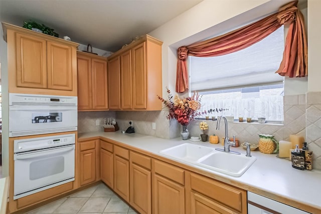 kitchen with a sink, decorative backsplash, light tile patterned floors, and light countertops