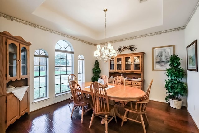 dining area featuring dark wood finished floors, a raised ceiling, and a chandelier