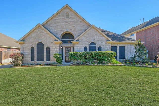 french provincial home featuring brick siding and a front lawn