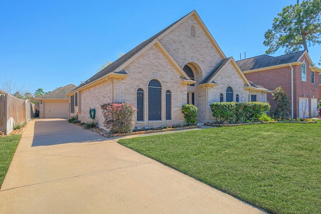 french country home featuring brick siding, a front lawn, fence, a garage, and driveway