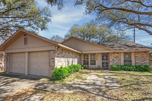 ranch-style home with a garage, brick siding, and driveway