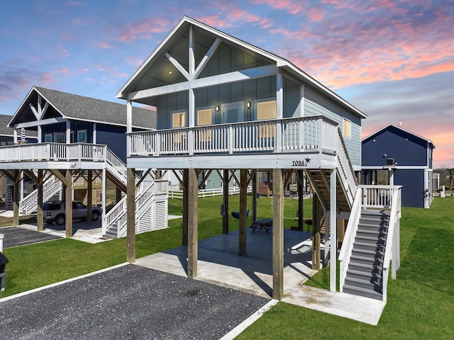 rear view of property with a carport, a lawn, board and batten siding, and stairs