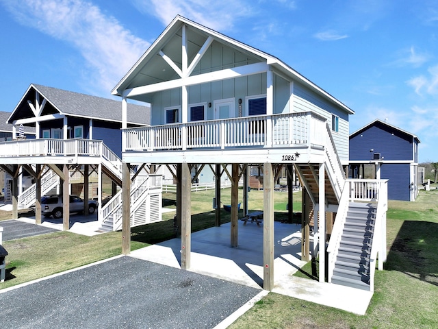 view of front of house featuring stairway, a carport, board and batten siding, and a front lawn