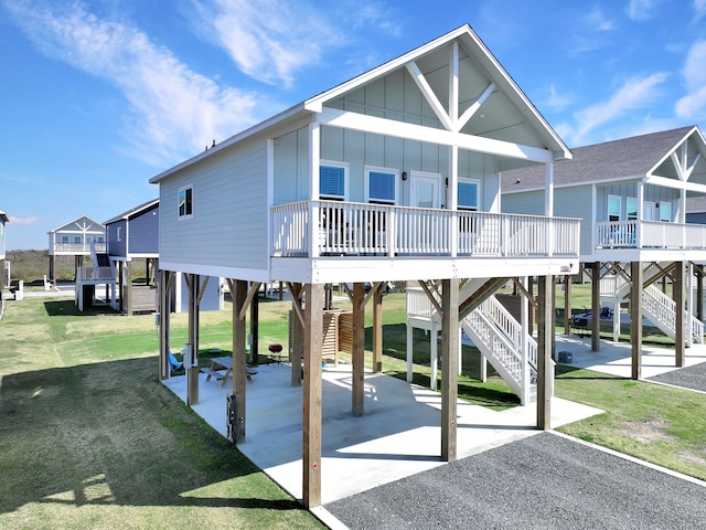 exterior space with driveway, stairs, a carport, a lawn, and board and batten siding