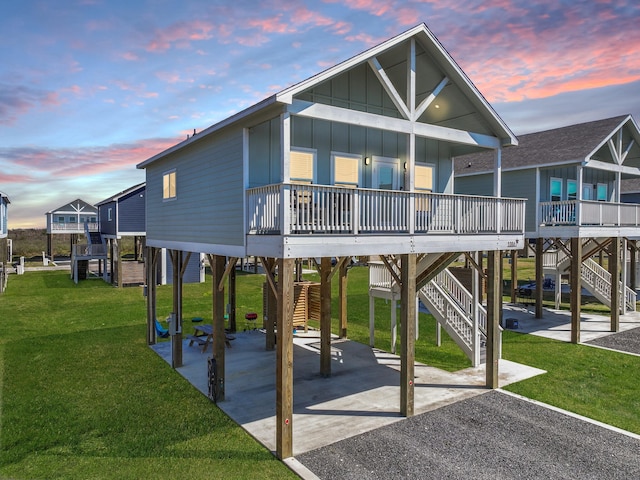 exterior space featuring driveway, stairs, a carport, a lawn, and board and batten siding