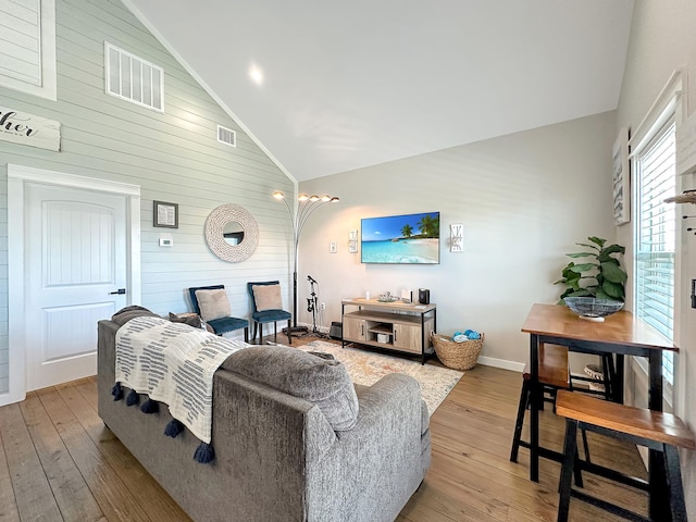 living area featuring light wood-type flooring, baseboards, high vaulted ceiling, and visible vents