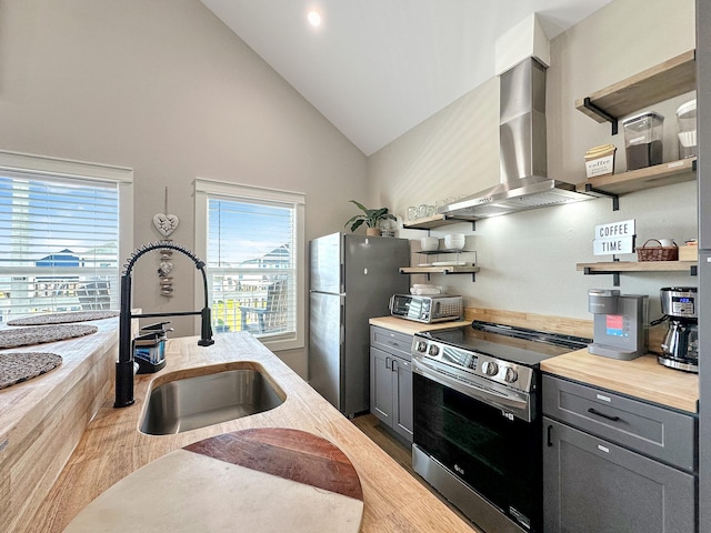 kitchen with open shelves, appliances with stainless steel finishes, a sink, and wall chimney range hood