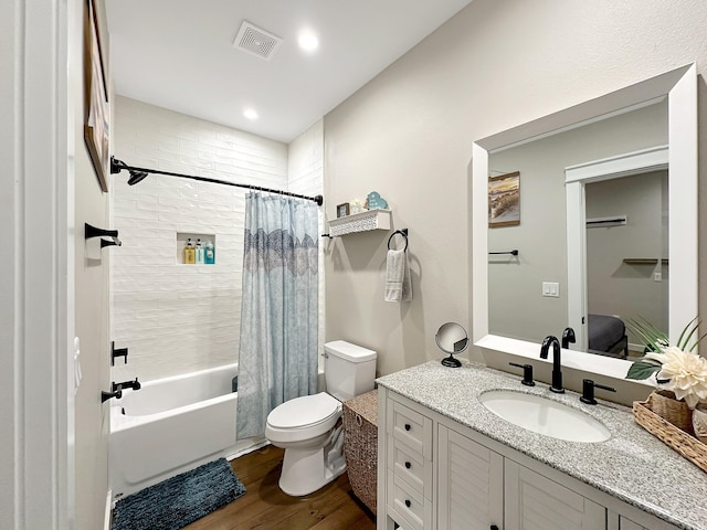 ensuite bathroom with visible vents, toilet, wood finished floors, shower / bath combination with curtain, and vanity