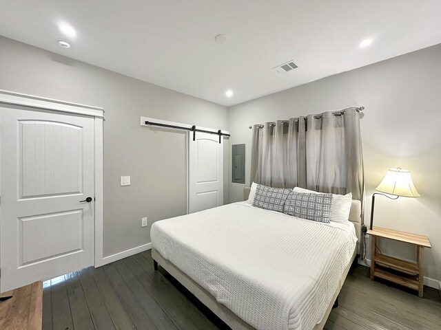 bedroom with visible vents, recessed lighting, a barn door, baseboards, and dark wood-style flooring