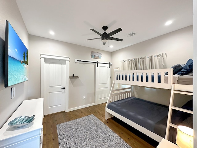 bedroom featuring visible vents, wood finished floors, recessed lighting, a barn door, and baseboards