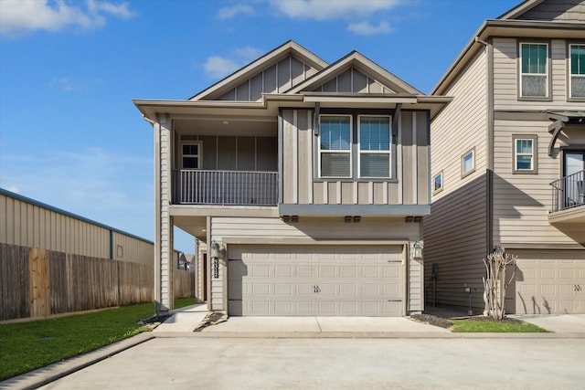 view of front of home featuring an attached garage, board and batten siding, driveway, and fence