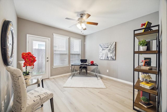 office area with baseboards, light wood-style floors, and ceiling fan