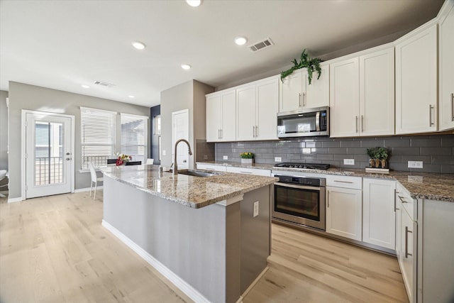 kitchen with visible vents, appliances with stainless steel finishes, light wood-style floors, and a sink