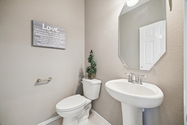 bathroom featuring toilet, baseboards, and a sink