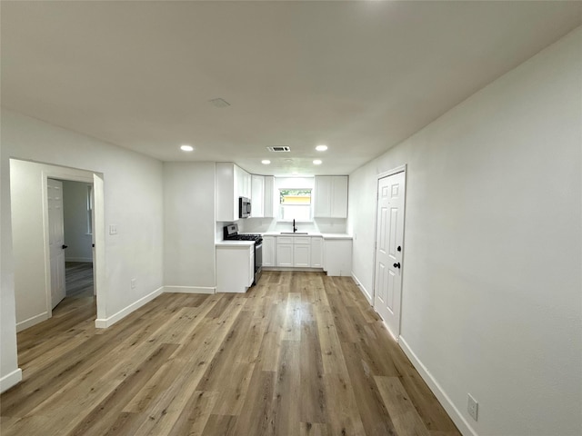 318 S Fulton St, Texas City, TX 77591 - kitchen featuring a sink, stainless steel range with gas stovetop, light wood-style flooring, white cabinetry, and recessed lighting