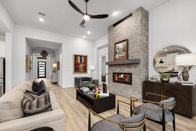 living area featuring a ceiling fan, light wood-style flooring, a fireplace, and visible vents