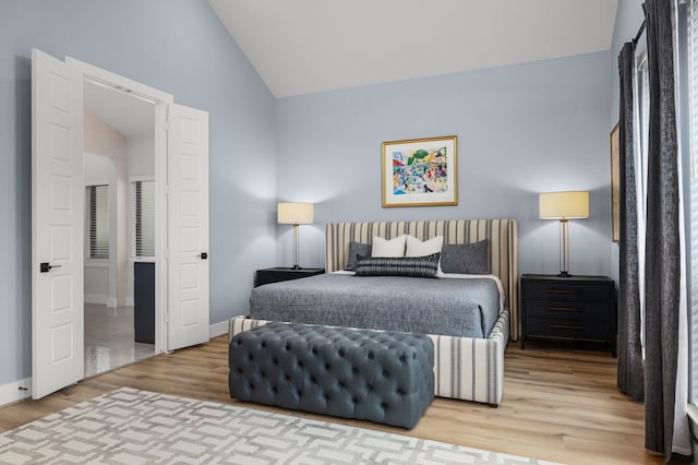 bedroom featuring baseboards, lofted ceiling, and wood finished floors