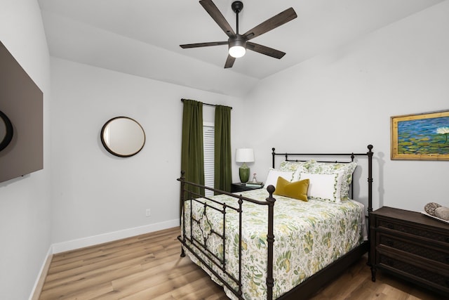 bedroom featuring a ceiling fan, vaulted ceiling, wood finished floors, and baseboards