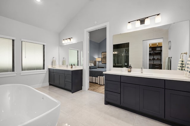 full bath with a freestanding tub, two vanities, ensuite bathroom, a sink, and lofted ceiling