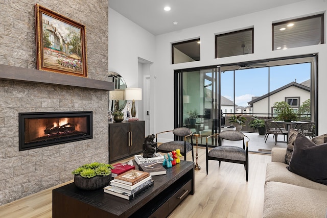 living room featuring recessed lighting, light wood-style floors, and a large fireplace