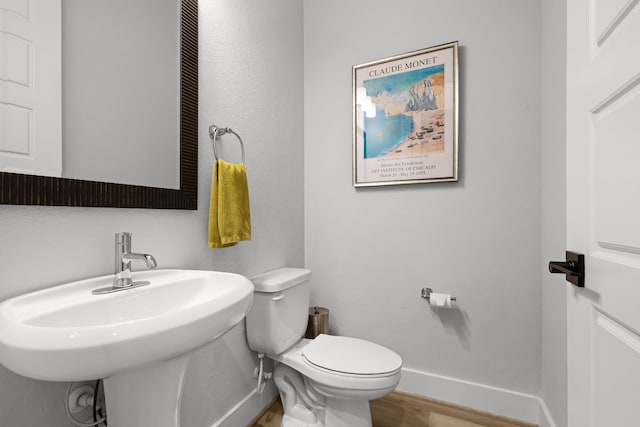 bathroom with a sink, baseboards, toilet, and wood finished floors