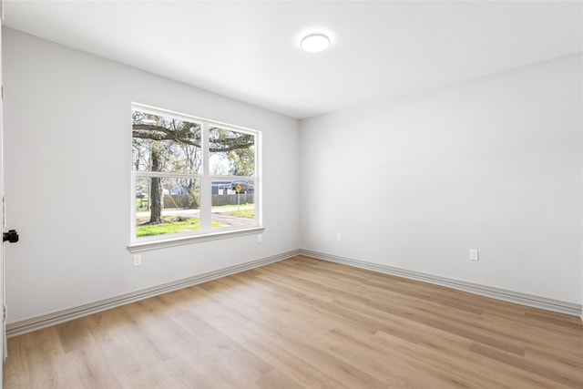 spare room featuring light wood finished floors and baseboards