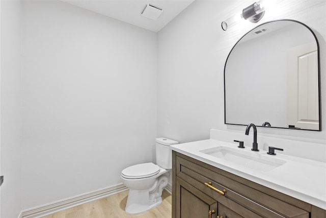 bathroom featuring vanity, wood finished floors, visible vents, baseboards, and toilet