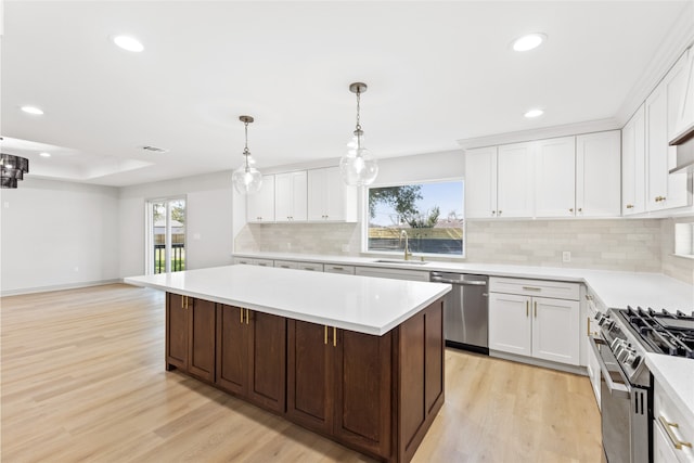 kitchen featuring light wood-style flooring, a sink, stainless steel appliances, light countertops, and a center island