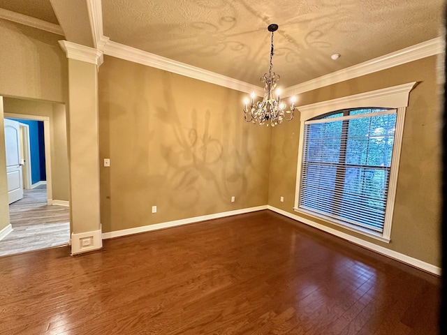 empty room with hardwood / wood-style flooring, decorative columns, baseboards, and ornamental molding