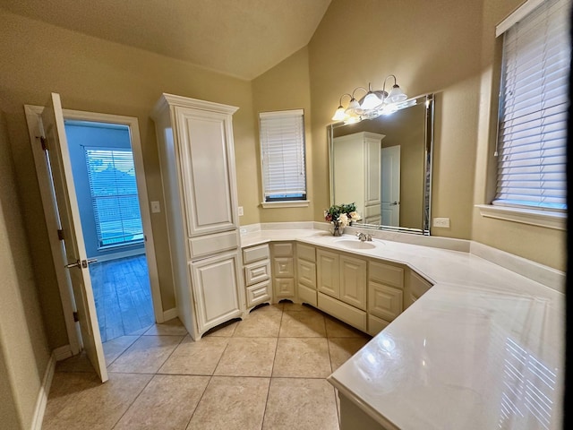 bathroom featuring tile patterned floors, vanity, baseboards, and vaulted ceiling