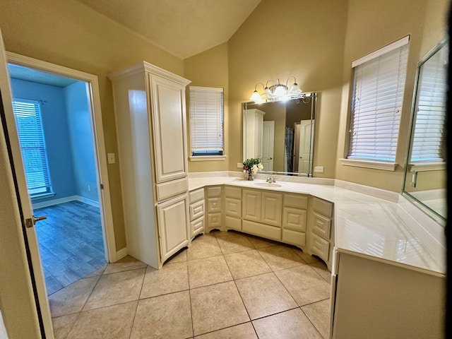 bathroom featuring vanity, tile patterned floors, a healthy amount of sunlight, and vaulted ceiling