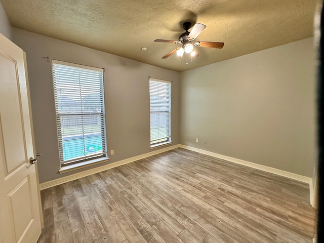 empty room with plenty of natural light, baseboards, and wood finished floors