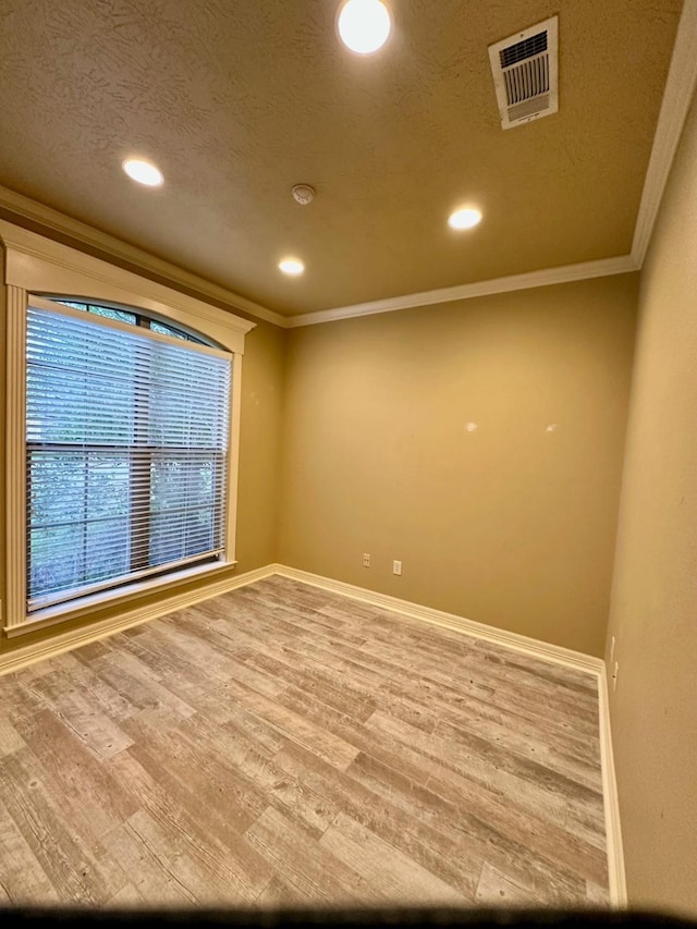 unfurnished room featuring visible vents, crown molding, baseboards, wood finished floors, and a textured ceiling