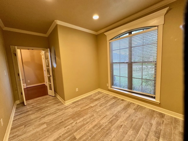 empty room with crown molding, light wood-style flooring, and baseboards