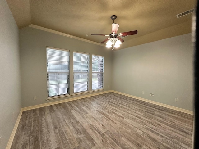 spare room featuring visible vents, baseboards, wood finished floors, and a ceiling fan