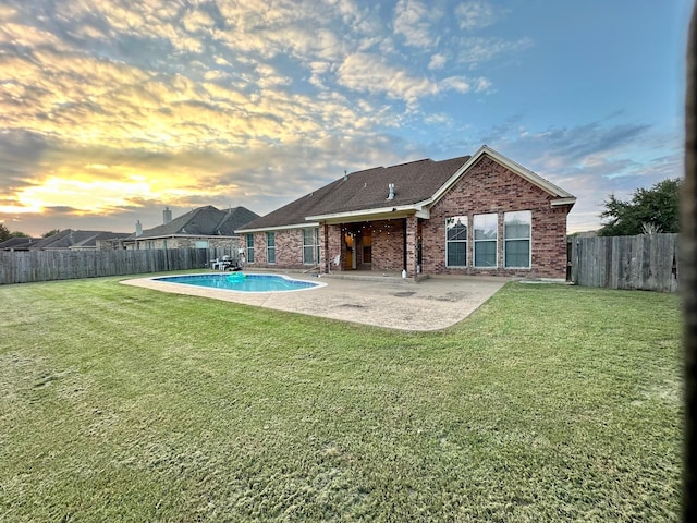 back of property with brick siding, a fenced in pool, a fenced backyard, a yard, and a patio area