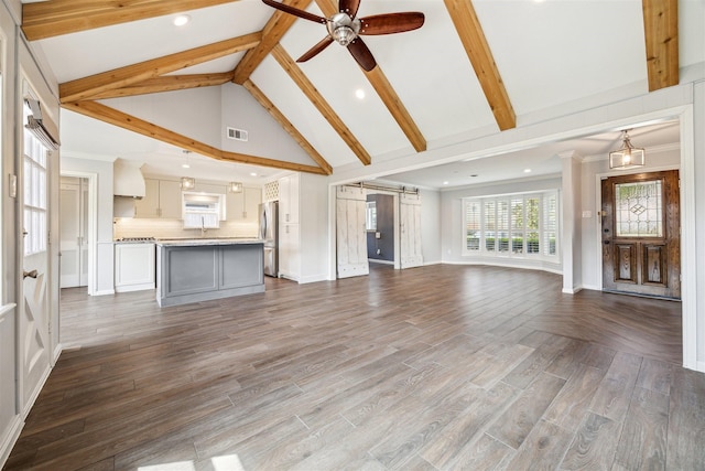 unfurnished living room featuring wood finished floors, visible vents, high vaulted ceiling, beam ceiling, and a barn door