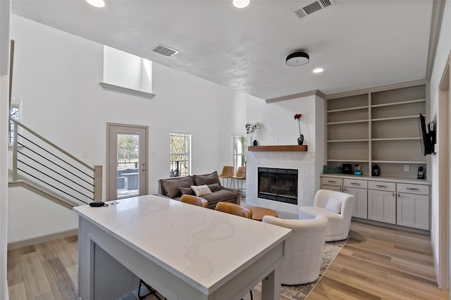 living room with a fireplace, stairs, light wood-style floors, and visible vents