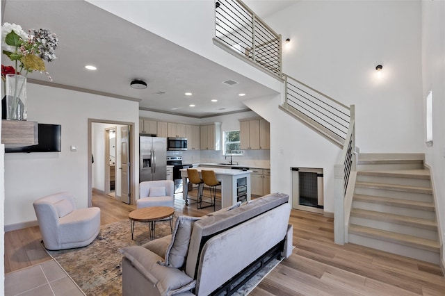 living area featuring visible vents, crown molding, stairs, and light wood finished floors