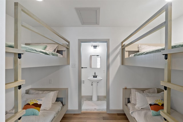 bedroom with baseboards, attic access, and wood finished floors