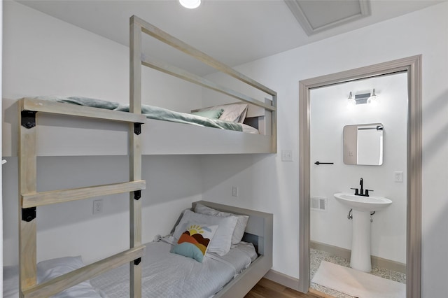 bedroom featuring wood finished floors, attic access, visible vents, and baseboards