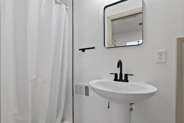 full bath with visible vents, a shower with shower curtain, and a sink