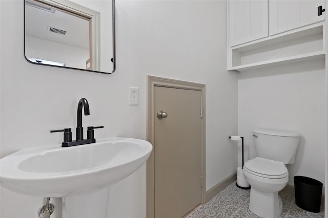 half bathroom with visible vents, baseboards, toilet, tile patterned floors, and a sink