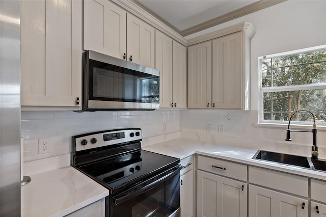 kitchen with backsplash, light stone countertops, appliances with stainless steel finishes, and a sink