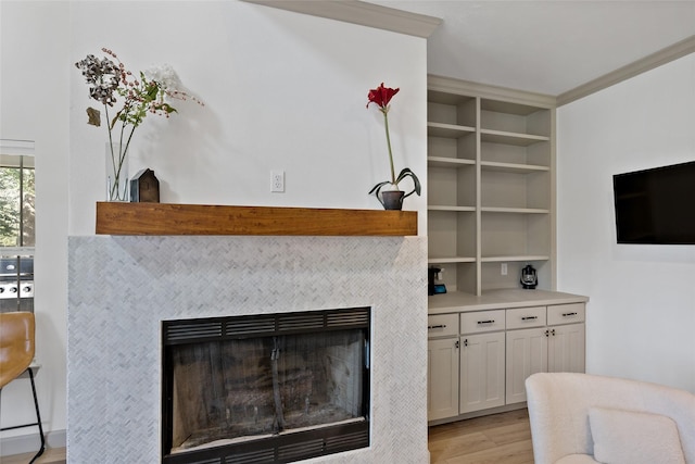 room details featuring a tiled fireplace, built in features, and wood finished floors