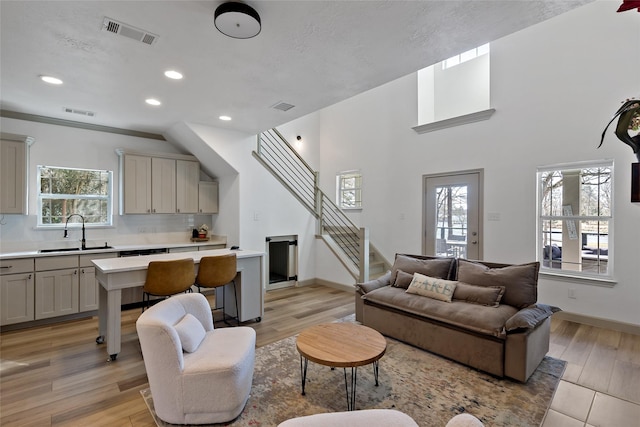 living area featuring a wealth of natural light, visible vents, and stairway