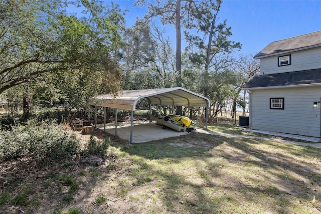 view of yard with a carport, central AC unit, and dirt driveway